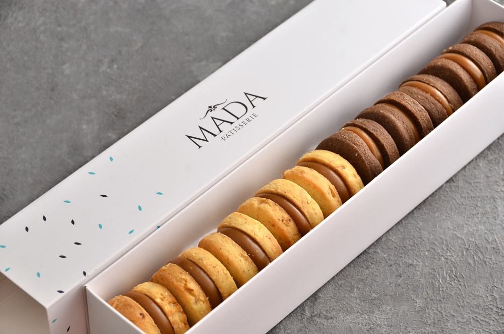Caja de 10 alfajores sablée artesanales de almendra y chocolate con dulce de leche de Mada Patisserie en Belgrano.